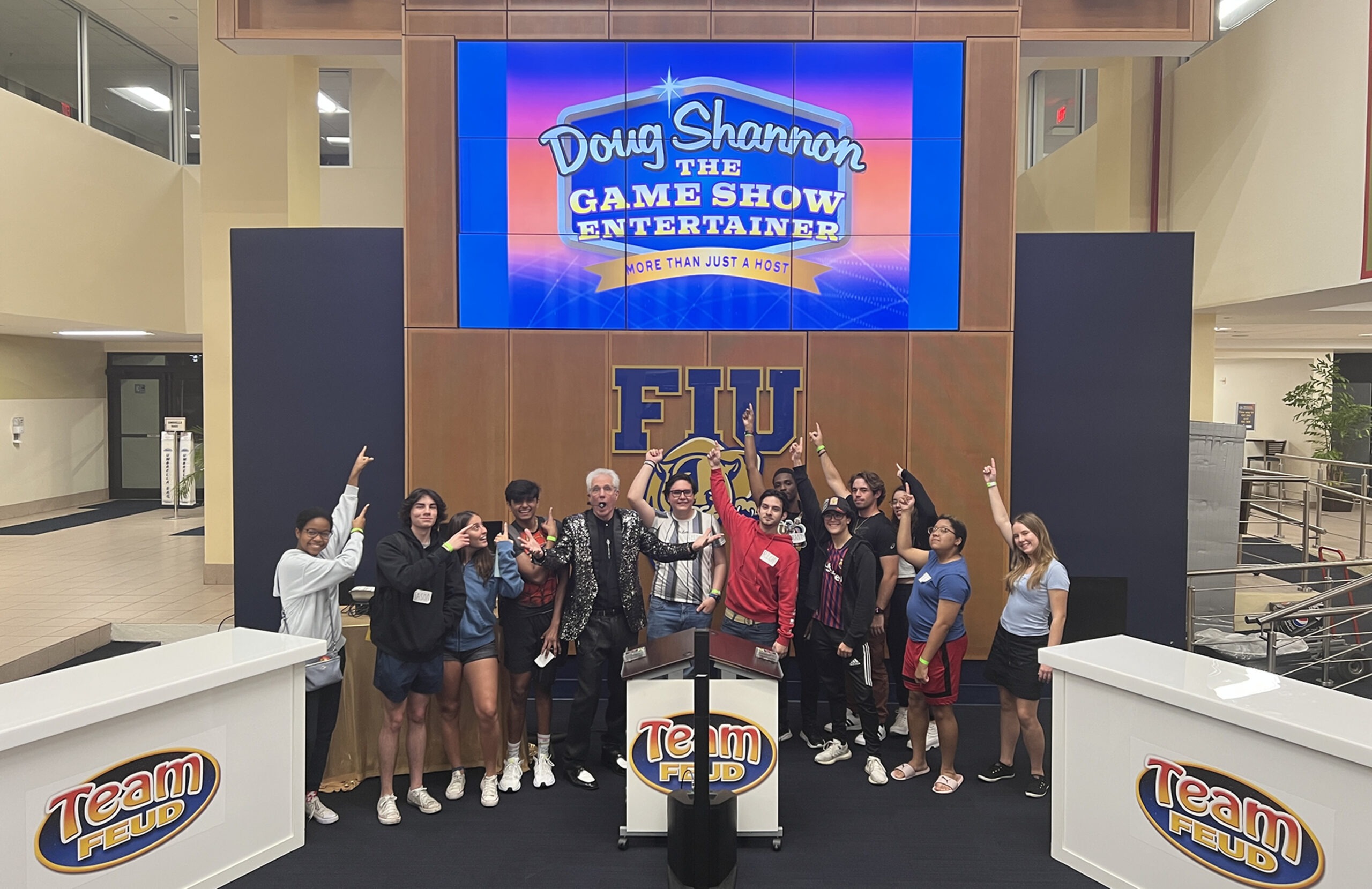 Two Team Feud With Doug Shannon at FIU with students pointing at Logo