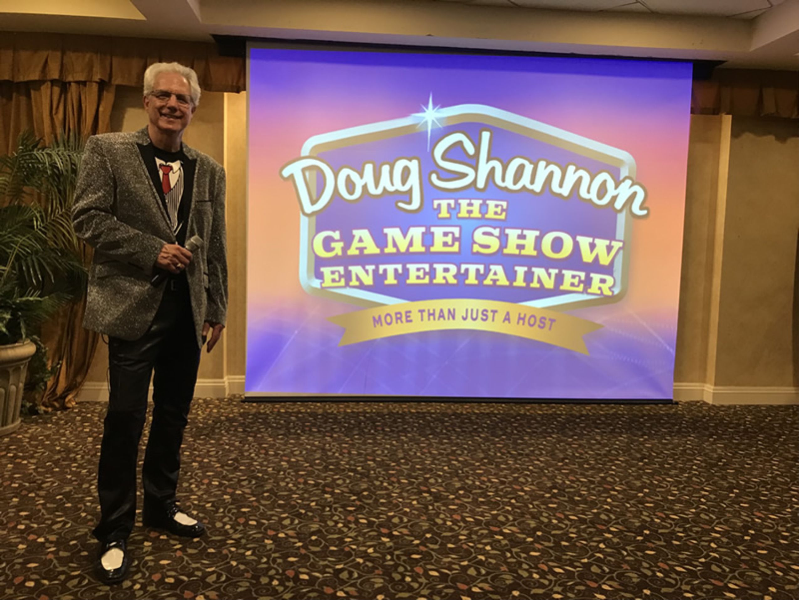 Doug standing next to Logo on screen